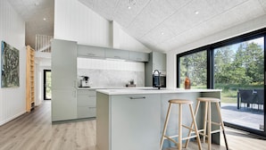 A modern kitchen with a large island, bar stools, and a view of the outdoors. - Newly built summer house full of luxury (Hals)
