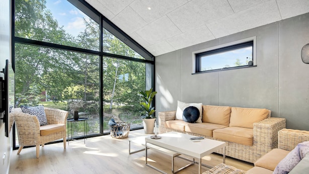 A modern living room with large windows, a sofa, a coffee table, and wicker furniture. - Newly built summer house full of luxury (Hals)