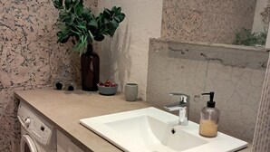 A compact bathroom with a washing machine, a sink, a soap dispenser, and a potted plant. - Beautiful holiday home on an undisturbed plot (Rødby)