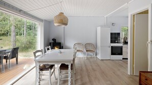A modern kitchen with white cabinets, a white refrigerator, and a black oven. - Charmantes Sommerhaus in der Nähe eines fantastischen Sandstrandes (Åkirkeby)