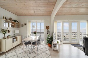Una cocina moderna con armarios blancos, una mesa de comedor con sillas, un ventanal y vistas al exterior.