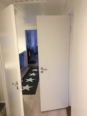 Ein Flur mit einer weißen Tür, einem Teppich mit Sternenmuster und einem Essbereich im Hintergrund.