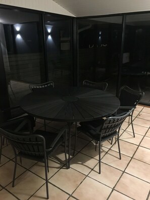 A round table with six chairs, a glass partition, and tiled flooring.