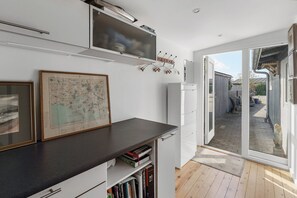 A kitchen with a flat-screen TV, a map, and a door leading to a patio. - Inviting cottage by the beach with a lake view (Karrebæksminde)