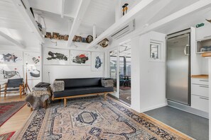 A modern living room with a black sofa, patterned rug, and artwork on the walls. - Inviting cottage by the beach with a lake view (Karrebæksminde)
