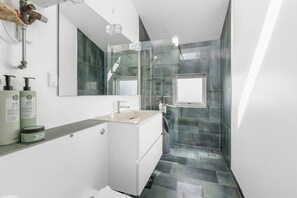 A modern bathroom with a white vanity, a glass shower enclosure, and a large mirror. - Inviting cottage by the beach with a lake view (Karrebæksminde)