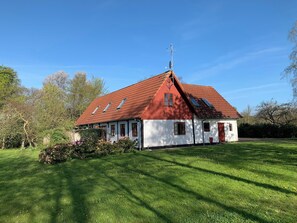 A red-roofed building with a white facade, surrounded by a grassy area and trees. - Idyllic country house on Bornholm (Nexø)