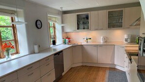 Cocina moderna con armarios blancos, lavavajillas y ventana con vistas a follaje.