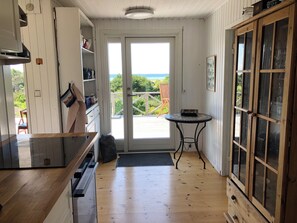 A kitchen with a wooden floor, a small round table, and a view through the door.
