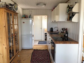 Eine kleine Küche mit Kühlschrank, Holzschränken, Spüle und Herd.