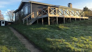 A house with a wooden deck and a staircase leading to a second-story balcony. - Nice summer house with sea view (Jægerspris)