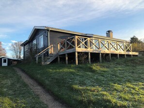 A house with a wooden deck and a staircase leading to a second-story balcony.