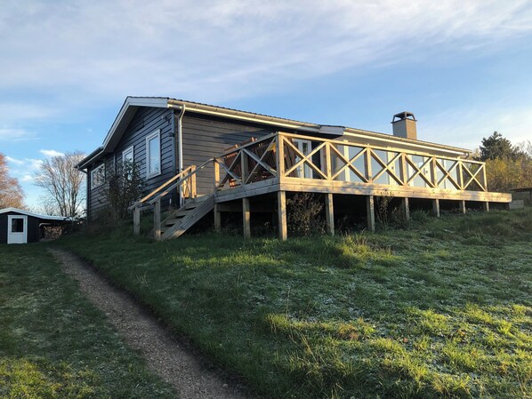 Ein Haus mit einer Holzterrasse und einer Treppe, die zu einem Balkon im zweiten Stock führt.