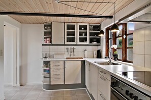 A modern kitchen with white cabinets, a built-in oven, and a large window. - Lovely fishermans cottage with seaview (Allinge)