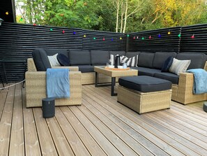 A deck with wicker furniture, a black sofa, and a table with a tray.