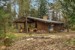 A rustic cabin with a covered porch, a fireplace, and a stack of firewood. - Nice summer house in the middle of the forest (Store Fuglede)