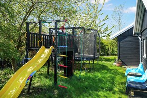Ein Spielplatz mit Rutsche, Klettergerüst und Trampolin.