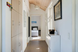 A hallway with a bed, a white cabinet, and a framed picture on the wall.