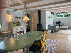 Un comedor con una mesa, sillas, una lámpara colgante, una estantería, una chimenea y vistas al exterior.