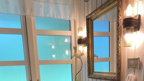 A bathroom with a white sink, a mirror with an ornate frame, a window with frosted glass, and a towel hanging on the wall. - Idyllic summer house at the water's edge (Spøttrup)