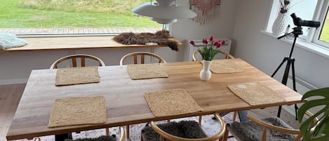 Un coin repas avec une table en bois, des sets de table en fibres tressées et des chaises recouvertes de peaux de fourrure.