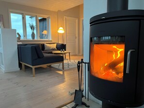 Un salon chaleureux avec un canapé, une petite table, une lampe et un poêle à bois.