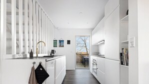 Una cucina moderna con mobili bianchi, un guanto da forno nero e un rubinetto in acciaio inossidabile.