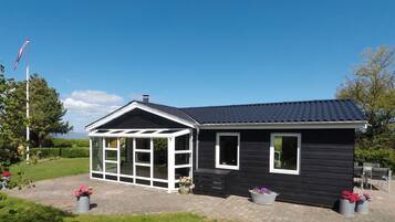 A black wooden house with a white window frame and a glass enclosure.