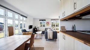 Eine moderne Küche mit Holzarbeitsplatten, ein Essbereich mit Tisch und Stühlen sowie ein Wohnzimmer mit einer Couch.