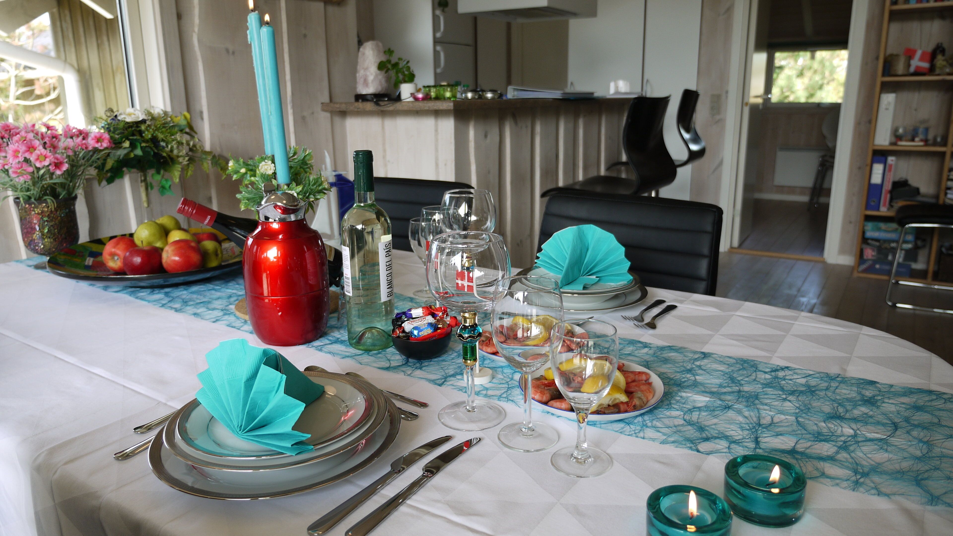 A dining table set with plates, cutlery, glasses, and candles.