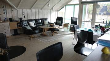 En moderne stue med sofa, lænestole, sofabord og fjernsyn.