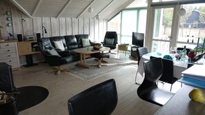 Una sala de estar moderna con un sofá, sillas, una mesa de centro y un televisor.