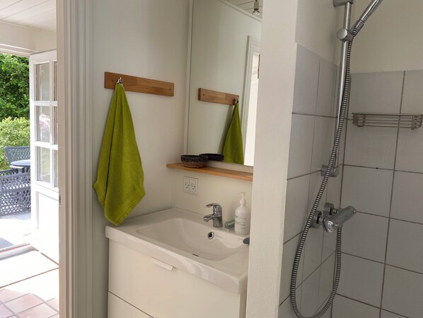 A bathroom with a sink, mirror, and shower.
