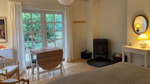 A room with a wooden desk, a chair, a bed, a fireplace, and a window with curtains. - Idyllically situated wooden house by the forest (Viborg)