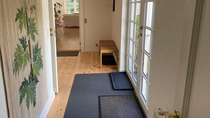 A hallway with a wooden bench, a mat at the entrance, and a door with glass panels. - Idyllically situated wooden house by the forest (Viborg)