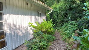 A pathway leading to a white building with a window and a door. - Idyllically situated wooden house by the forest (Viborg)