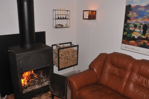 Ein Zimmer mit Kamin, einem braunen Ledersofa, einem gerahmten Kunstwerk und einem an der Wand befestigten Regal mit Kerzen.