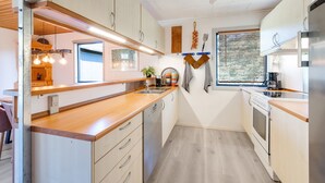 Une cuisine moderne avec des plans de travail en bois, des appareils en acier inoxydable et des luminaires suspendus.