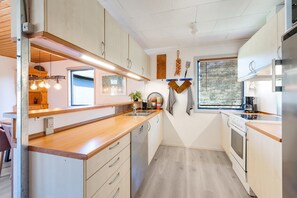 Une cuisine moderne avec des plans de travail en bois, des appareils en acier inoxydable et des luminaires suspendus.