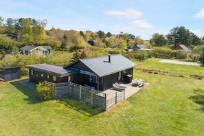 A residential property with a fenced yard, a covered outdoor seating area, and a house with a sloped roof.