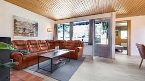 Un salon moderne avec un canapé en cuir, une table basse et une grande fenêtre agrémentée de rideaux.