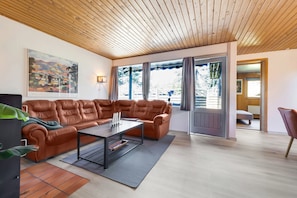 A modern living room with a leather sofa, a coffee table, and a large window with curtains.