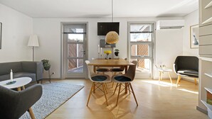 A modern living room with a sofa, dining table, chairs, and a TV.