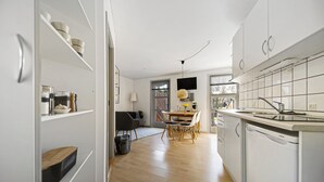 A modern kitchen with white cabinetry, a dishwasher, and a dining area with a table and chairs.