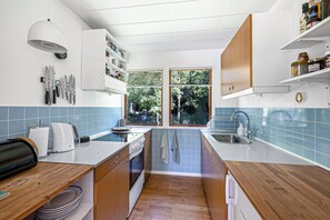 A modern kitchen with wooden cabinets, a built-in oven, and a window with a view of greenery.