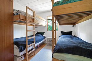 A dormitory room with bunk beds, a desk, and a window providing a view of the outdoors. - Beautiful summer house near forest and beach (Højby)