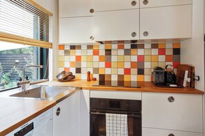 Una cocina moderna con un lavamanos de acero inoxidable, un protector contra salpicaduras colorido y un horno empotrado.