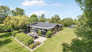 A modern house with a patio, surrounded by well-maintained lawns and trees. - Unique holiday home in quiet surroundings (Storvorde)