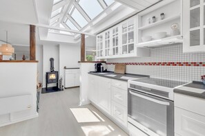 Une cuisine moderne avec des meubles blancs, une cuisinière encastrée et un puits de lumière.