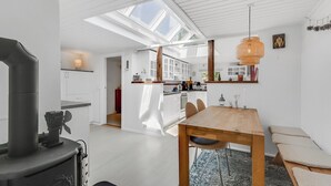 A modern kitchen with skylights, a dining area with a wooden table, and a visible stove. - Unique holiday home in quiet surroundings (Storvorde)